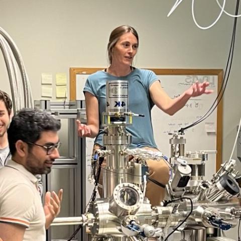 Female physicist speaking in lab behind equipment